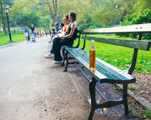 A detailed close-up of a reusable water container held by a person resting on a park bench